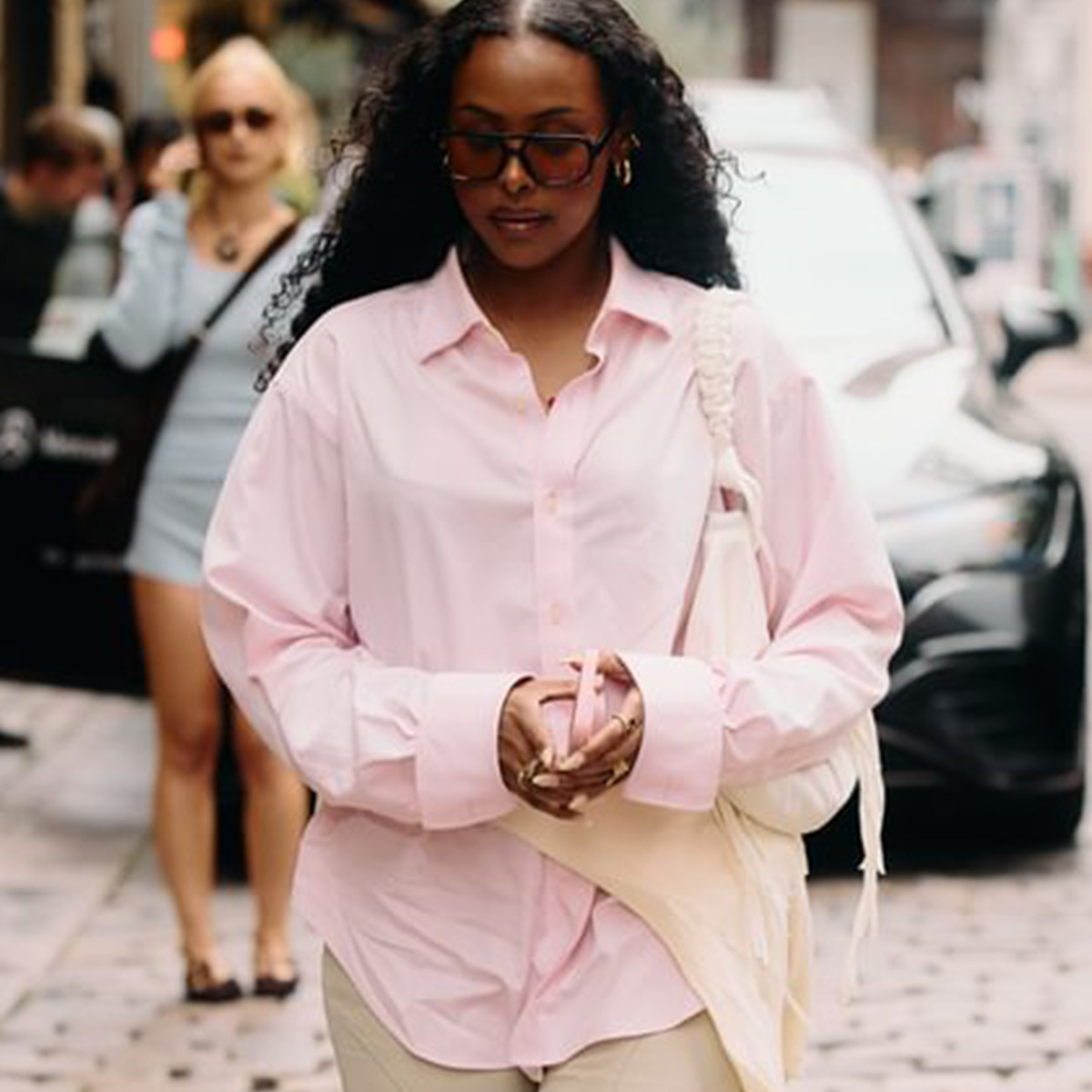 A Copenhagen Fashion Week attendee wearing a pink button-down shirt. 