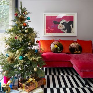 A living room with a decorated Christmas tree, graphic rug and a colourful sofa
