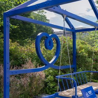 Blue swing chair under metal roof in garden area