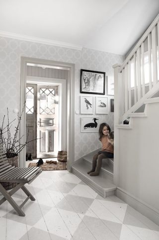 wood flooring painted in a diamond pattern in a white hallway with white painted banister