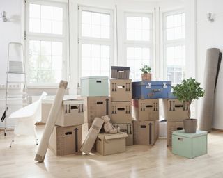 A stack of cardboard boxes in an empty apartment living room with white wall paint decor