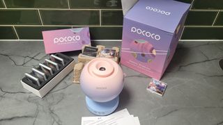 The Pococo projector on a work surface alongside extra disks and their packaging