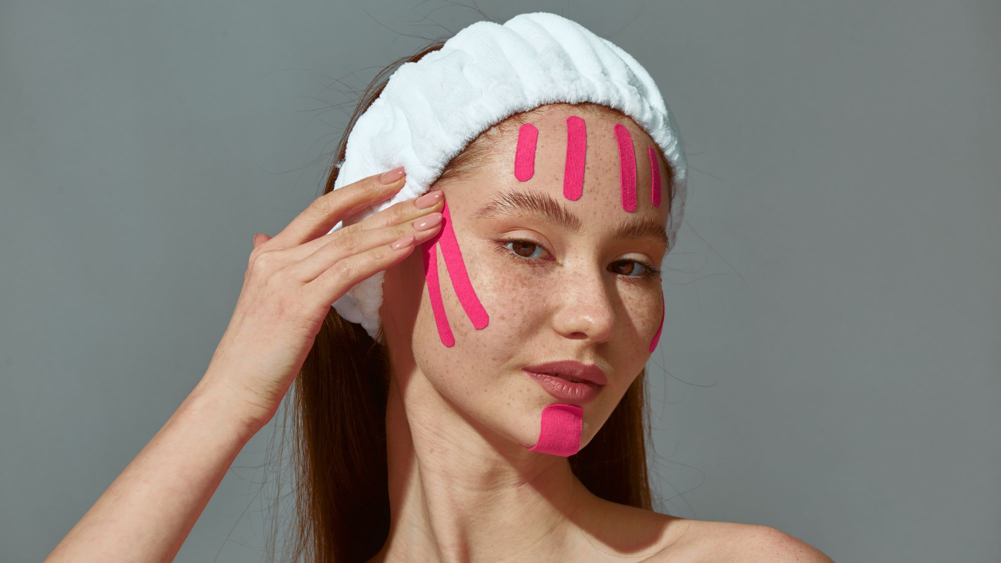 a woman with pink face tape on her face