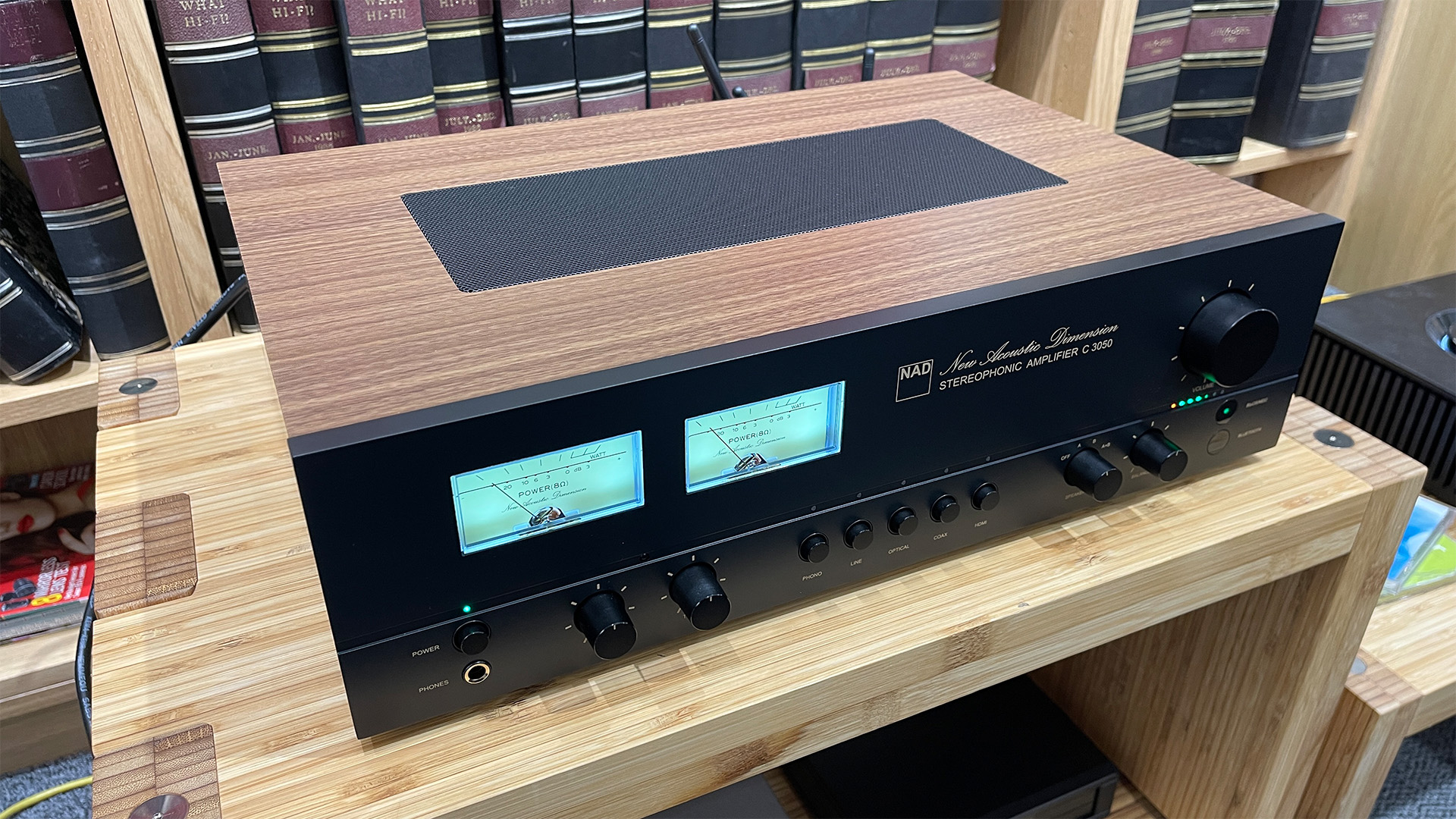 NAD C 3050 (with MDC2 BluOS-D module) streaming amplifier on wooden hi-fi rack in front of bookcase