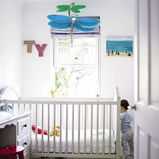 nursery room with baby and white baby cot