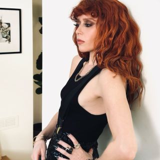 Natasha Lyonne with shaggy red hair and short fringe wearing black vest