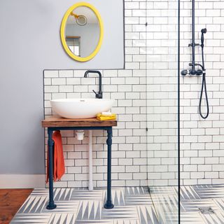 Bathroom with floor and wall tiles, industrial basin stand and yellow framed mirror
