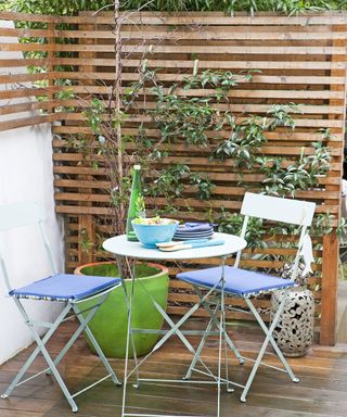 Wooden slat trellising next to small outdoor dining area