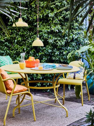Annie Sloan chalk paint in english yellow on outdoor furniture with living wall in background