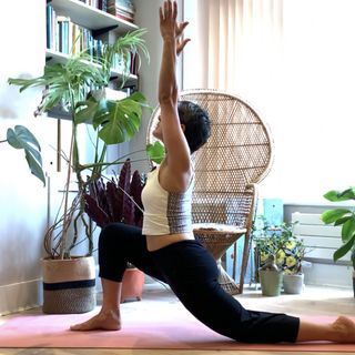 Yanar Alkayat doing yoga for hips crescent moon low lunge pose at home with plants in the background