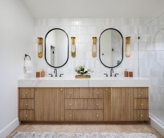 A bathroom with sconces on either side of the mirror