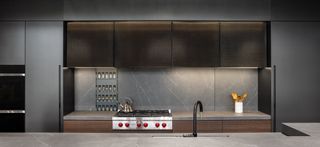 A dark-hued kitchen illuminated with under-cabinet lighting.