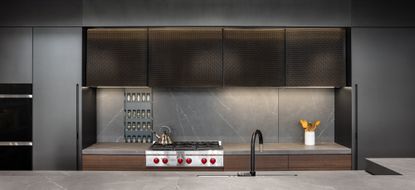 A dark toned kitchen lit up with undercabinet lights