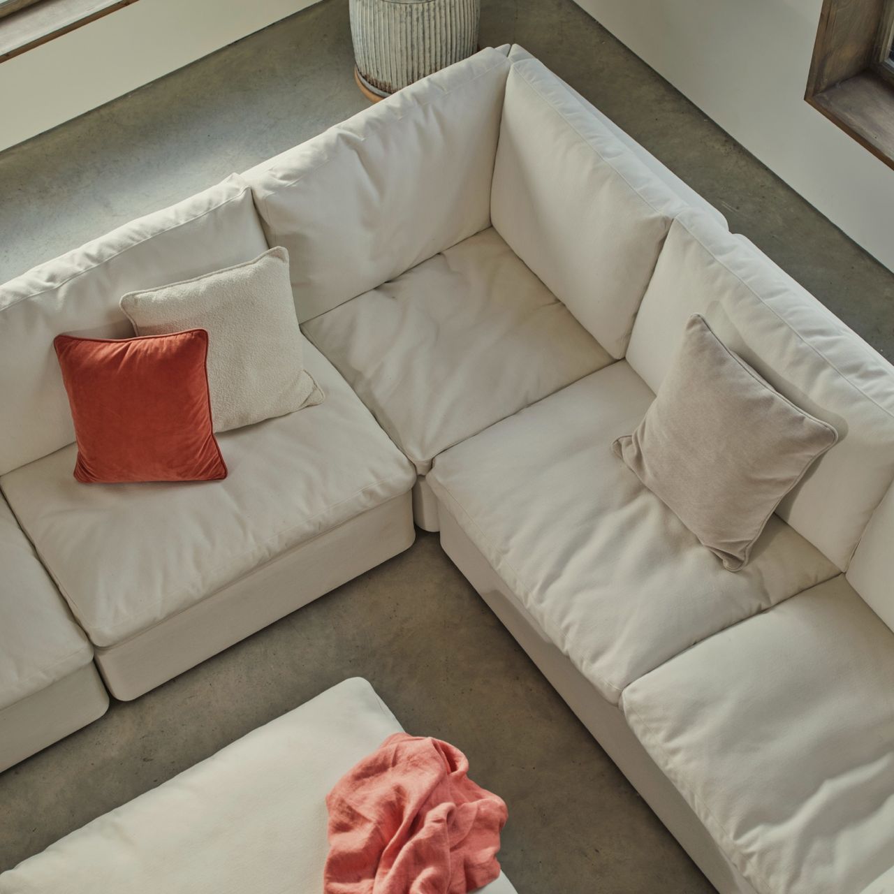 Swyft&#039;s Model 13 modular corner sofa in white with three tonal and contrasting cushions in a large airy living room