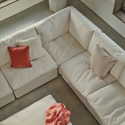 Swyft's Model 13 modular corner sofa in white with three tonal and contrasting cushions in a large airy living room