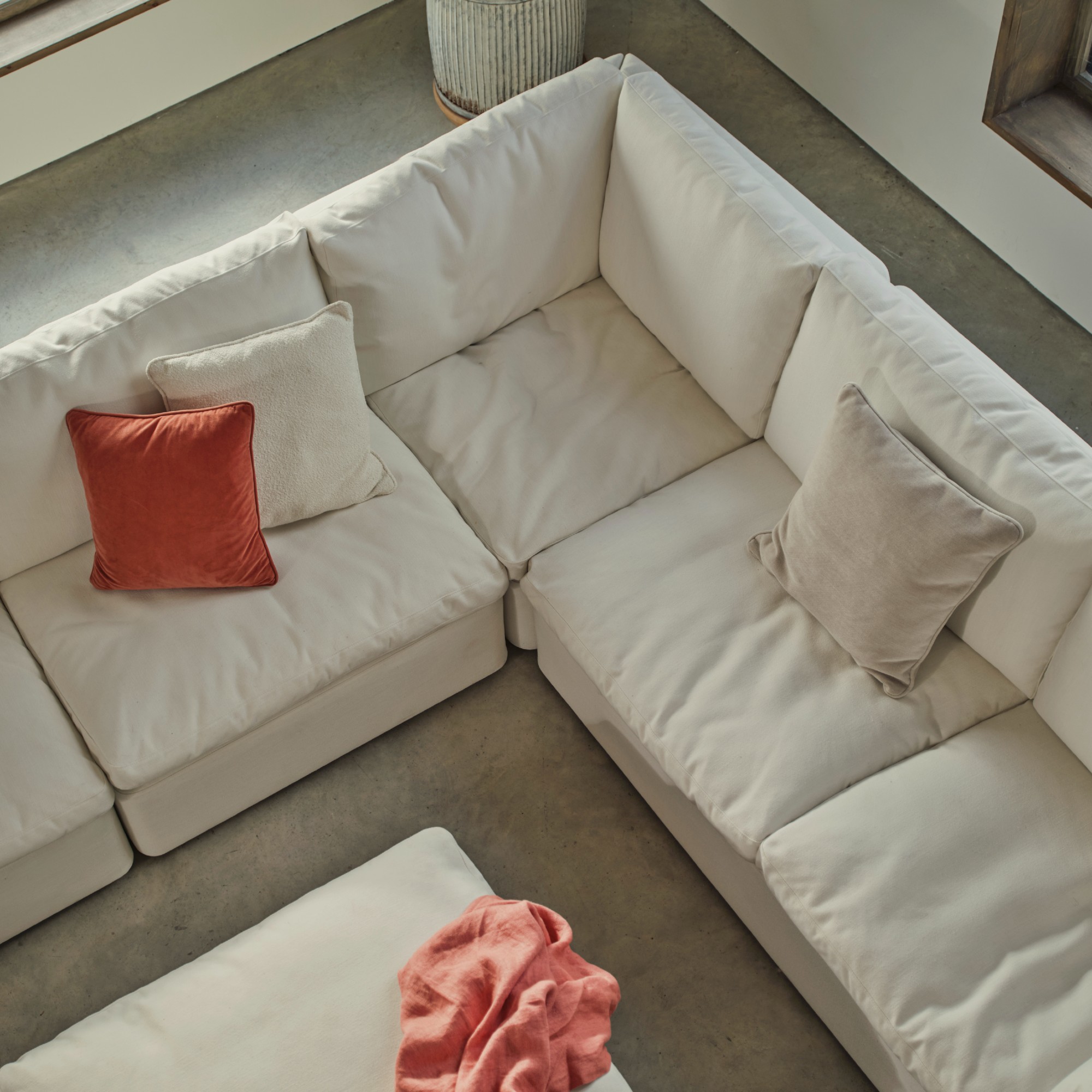 Swyft&#039;s Model 13 modular corner sofa in white with three tonal and contrasting cushions in a large airy living room