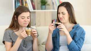Two women drinking coffee, looking disgusted