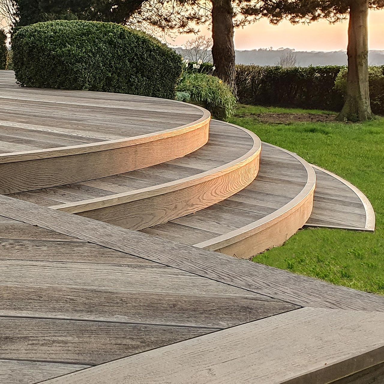 Curved decking steps leading down to a green lawn