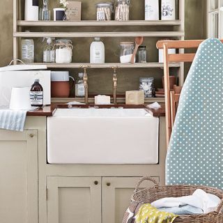 large butler sink with shelving and ironing board