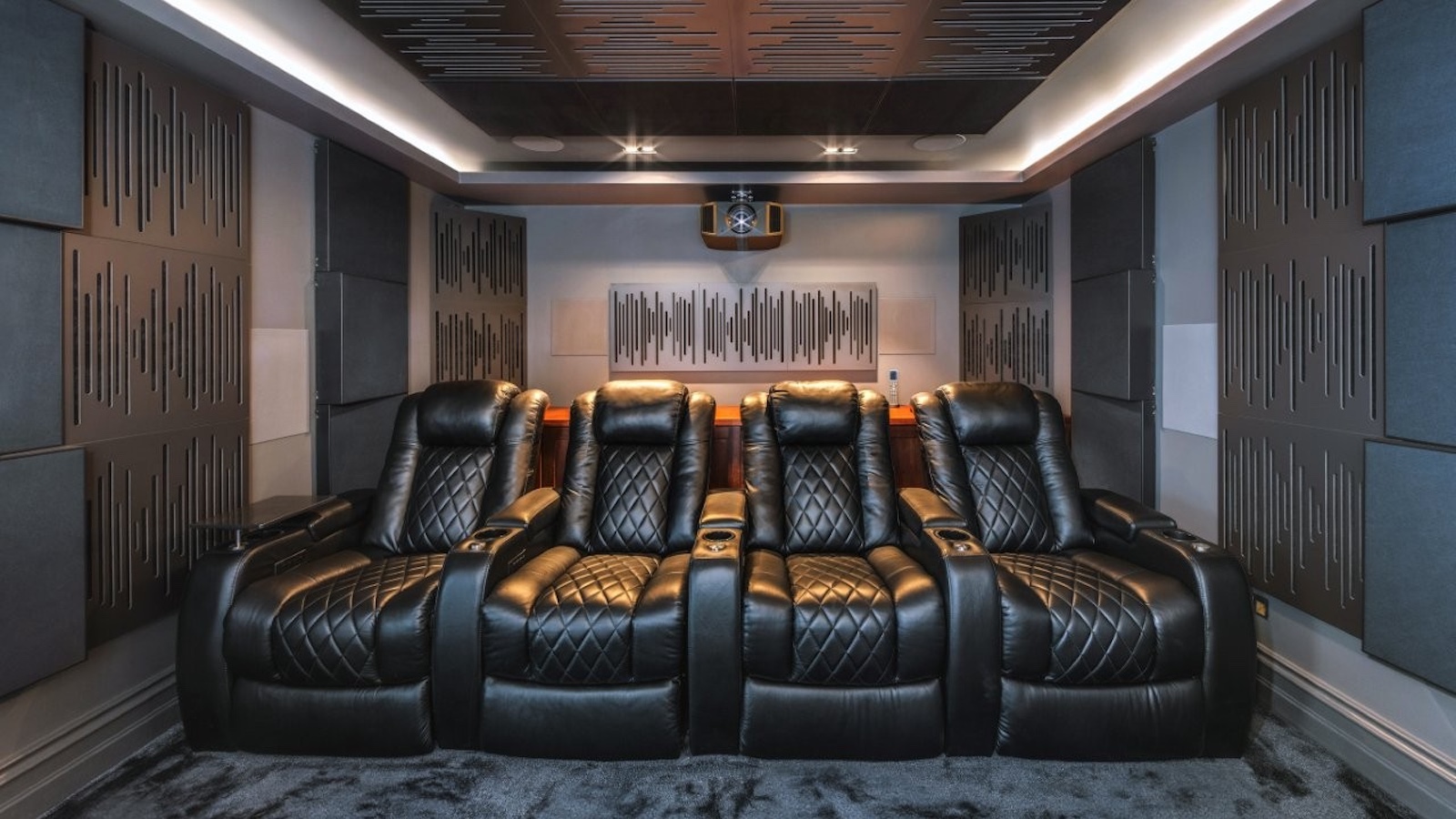 A photo of a custom-installed home cinema room featuring a 4K projector, theatre seating and clever acoustic treatment