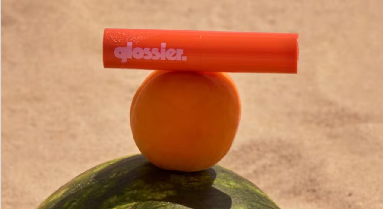 glossier balm on an orange