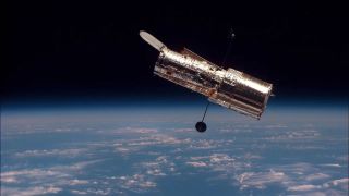 An image of the Hubble Space Telescope hovering in Earth's orbit.