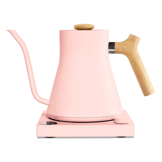 A pastel pink curved kettle with pour over spout and wooden handle