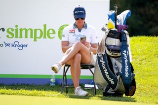 Charley Hull on her phone during a round of golf and sat on a chair