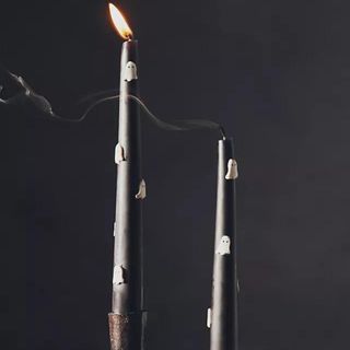 Two black taper candles with white ghost decorations from Anthropologie