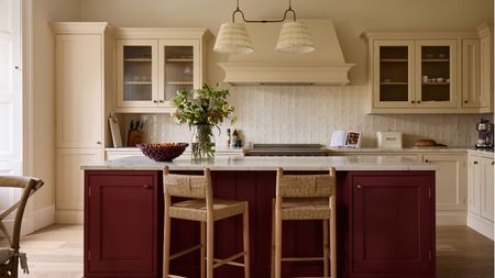 Cream kitchen with a dark red kitchen island and rattan bar stools