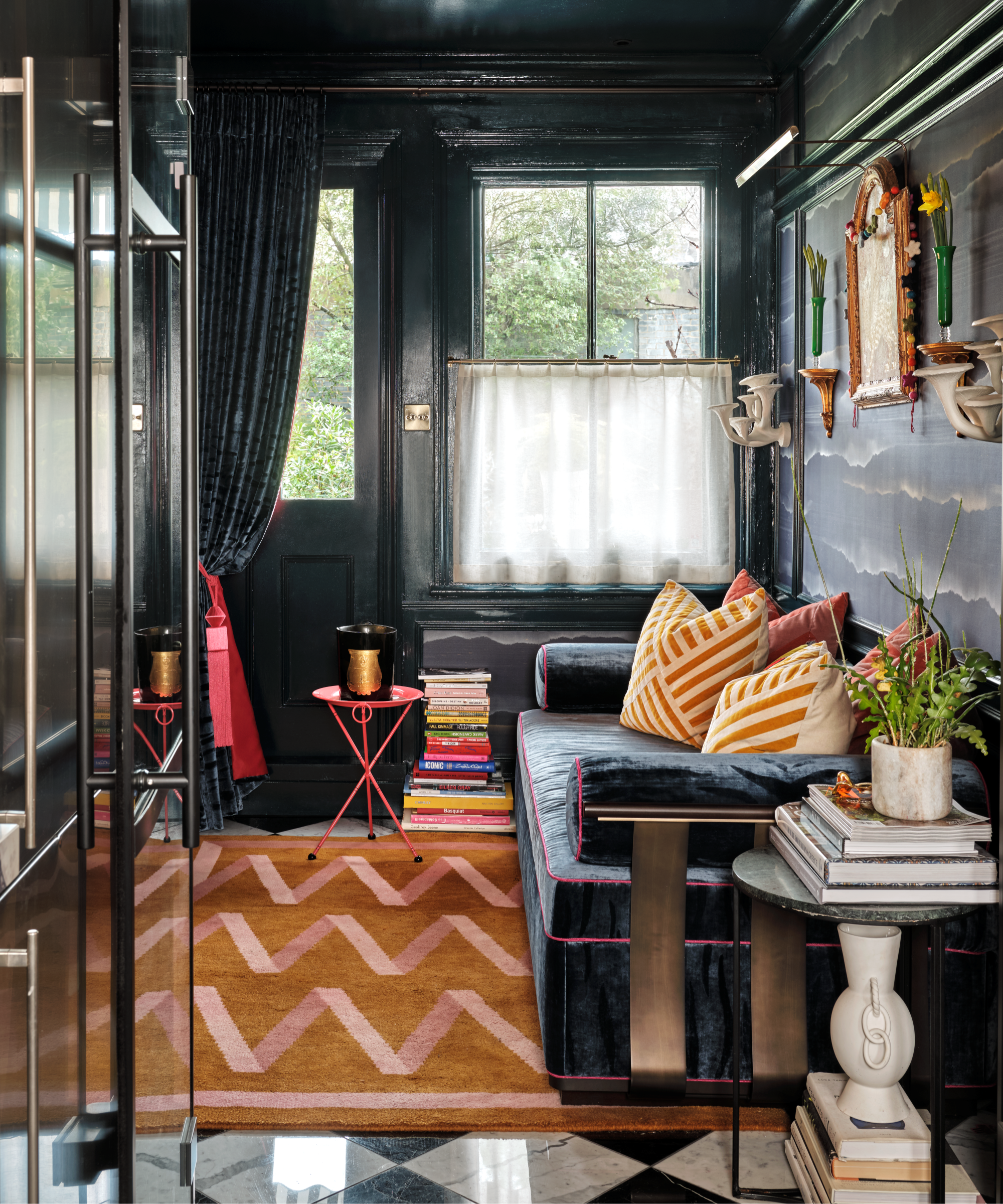a snug room with dark walls, a dark couch, and a bright orange rug with zig zag pink lines
