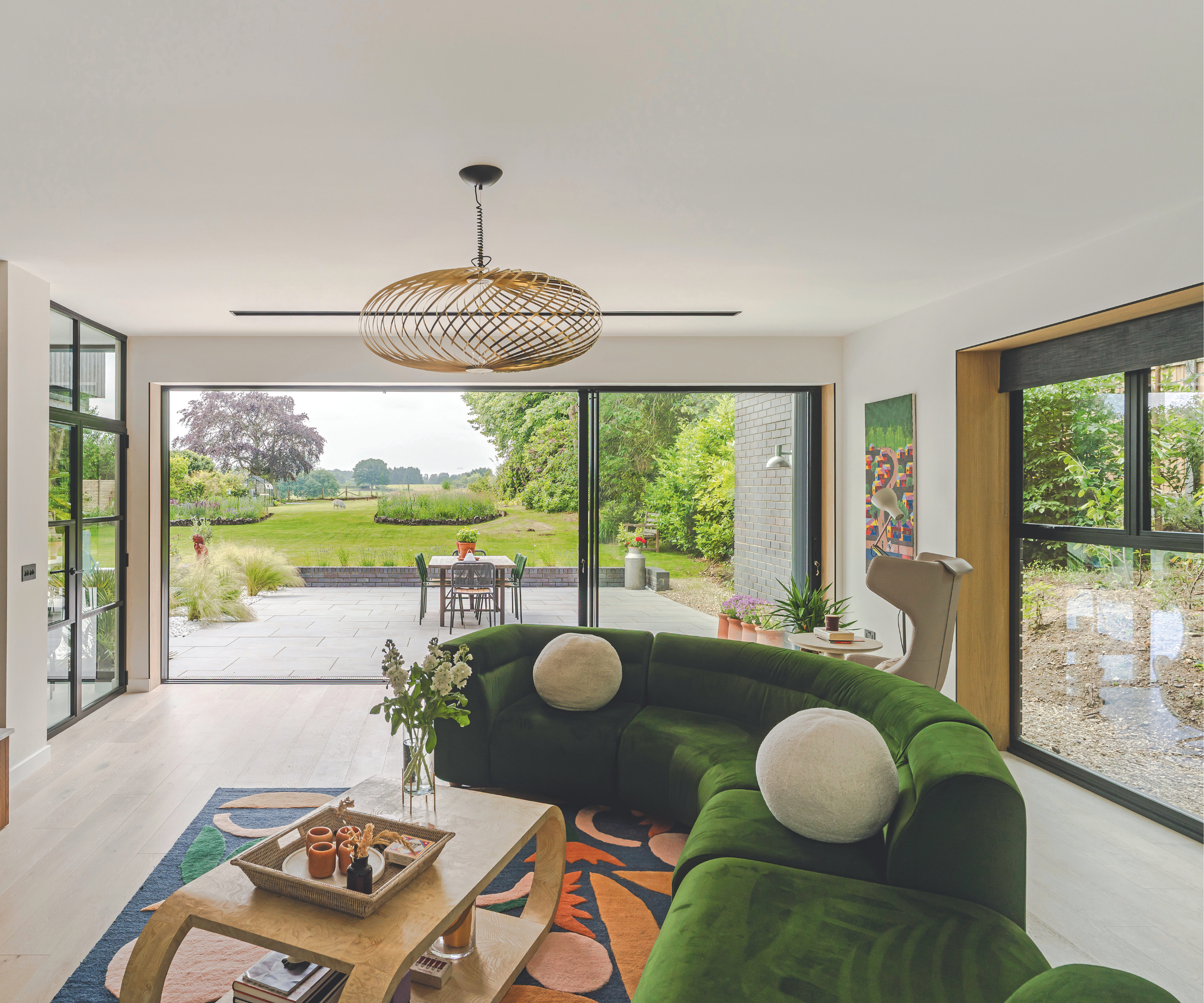 Living room with green curved sofa and sliding doors leading onto the patio with views across the garden