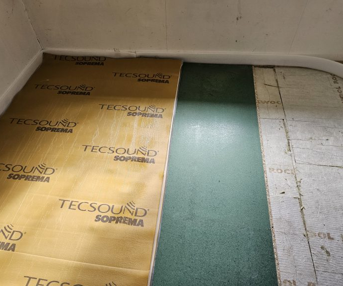 Layers of sound insulation shown on a floor, including a Tecsound membrane and Rockwool mineral wool
