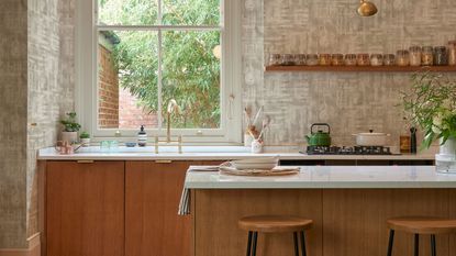 Warm kitchen space with wooden island, tall stools, and two glass pendant lights