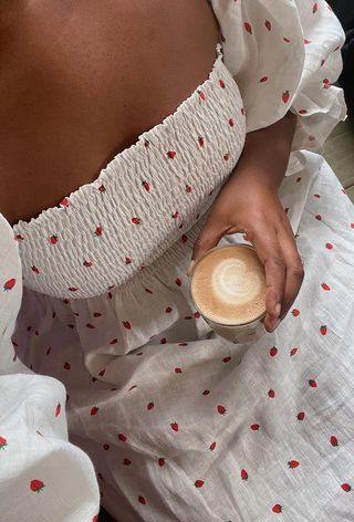 a close-up photo of a woman wearing a print dress with strawberries