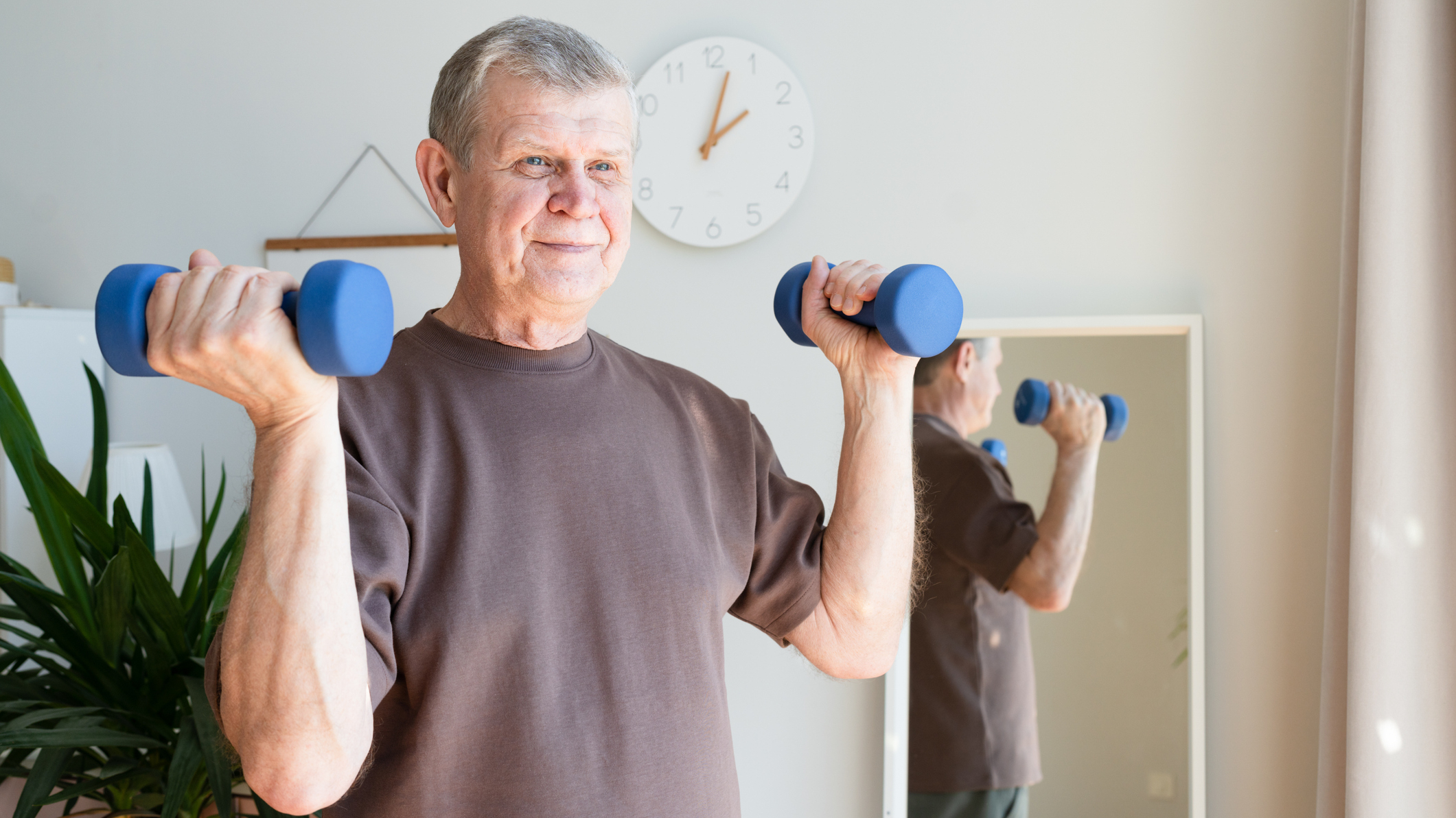Senior man holding dumbbells at home
