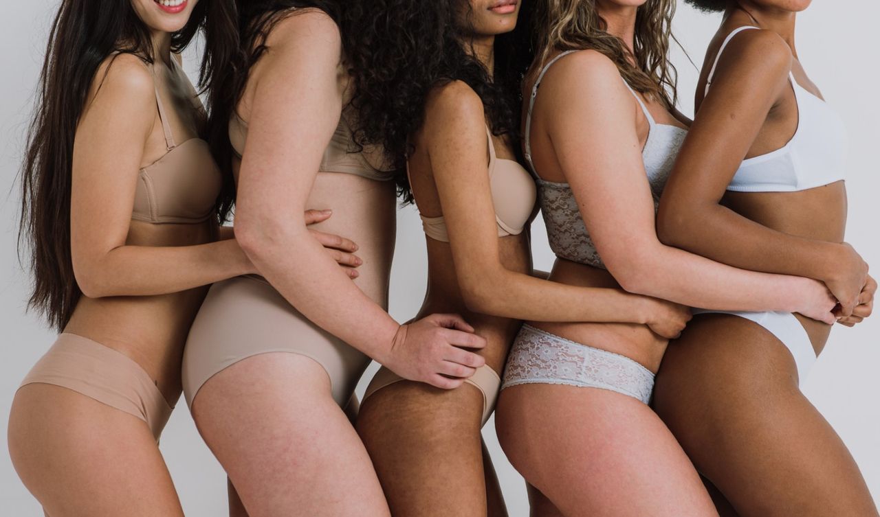 Midsection Of Multi-Ethnic Women In Bras Against Gray Background - stock photo