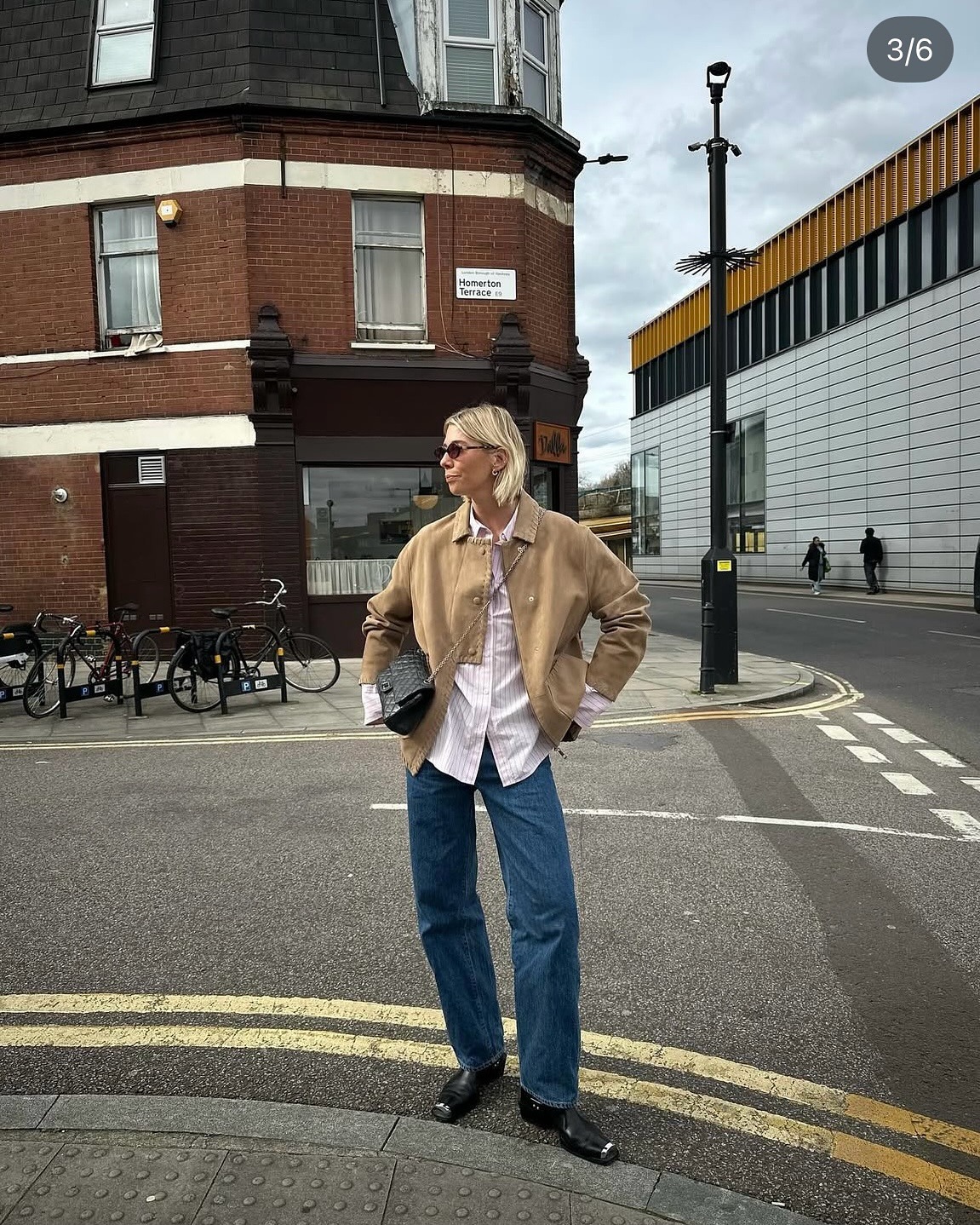 A woman posing on the street with a sleek, ashy blonde bob