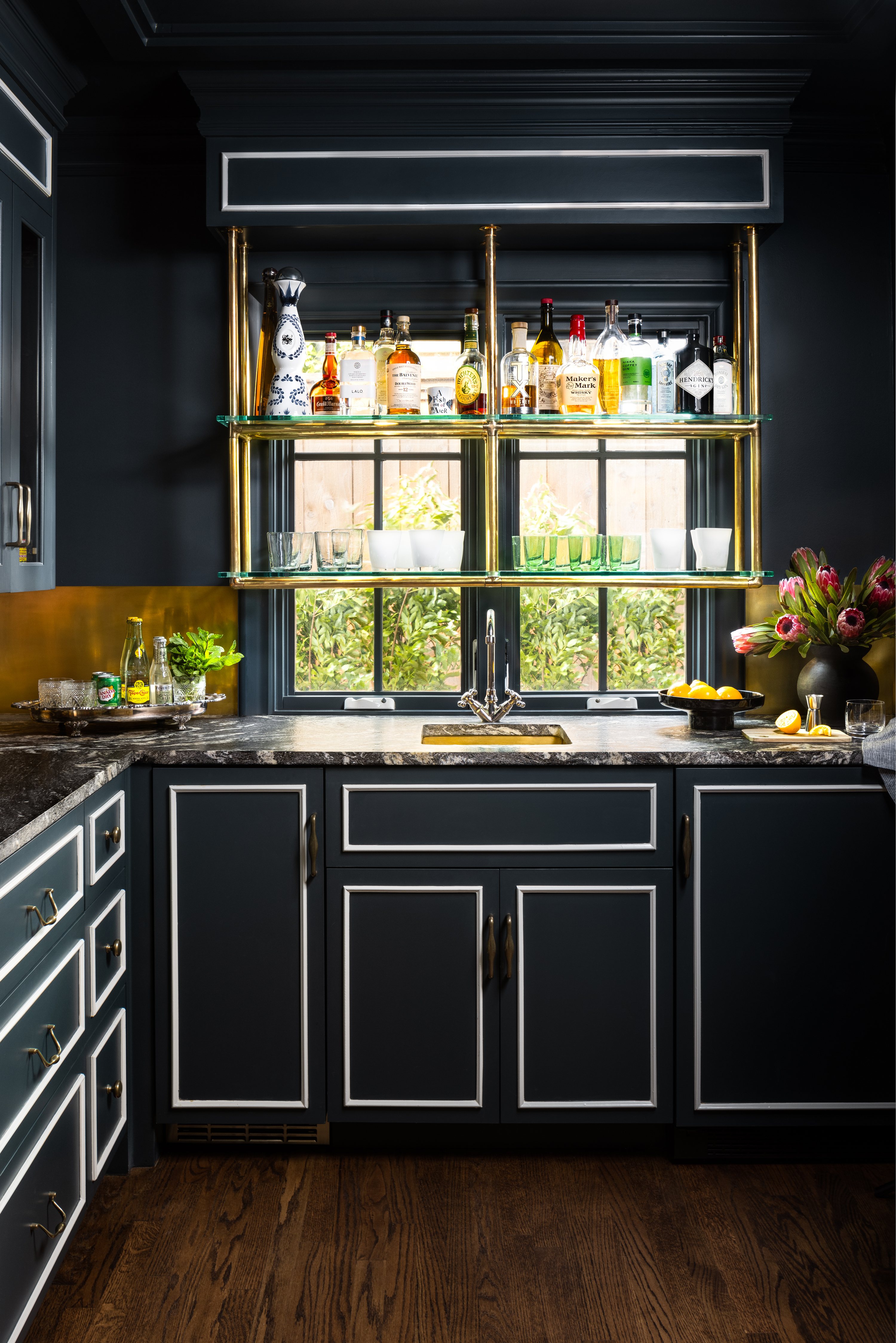 A kitchen painted in dark tones with white detailing to make the color pop