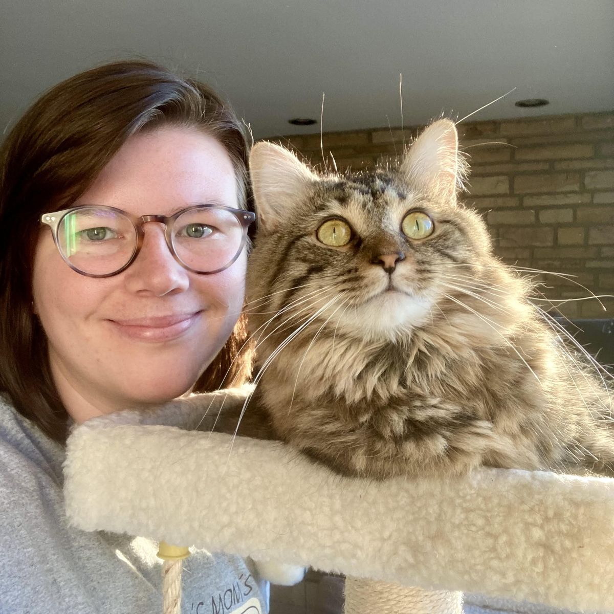Laura next to her cat Nellie who is sitting on a cat tree