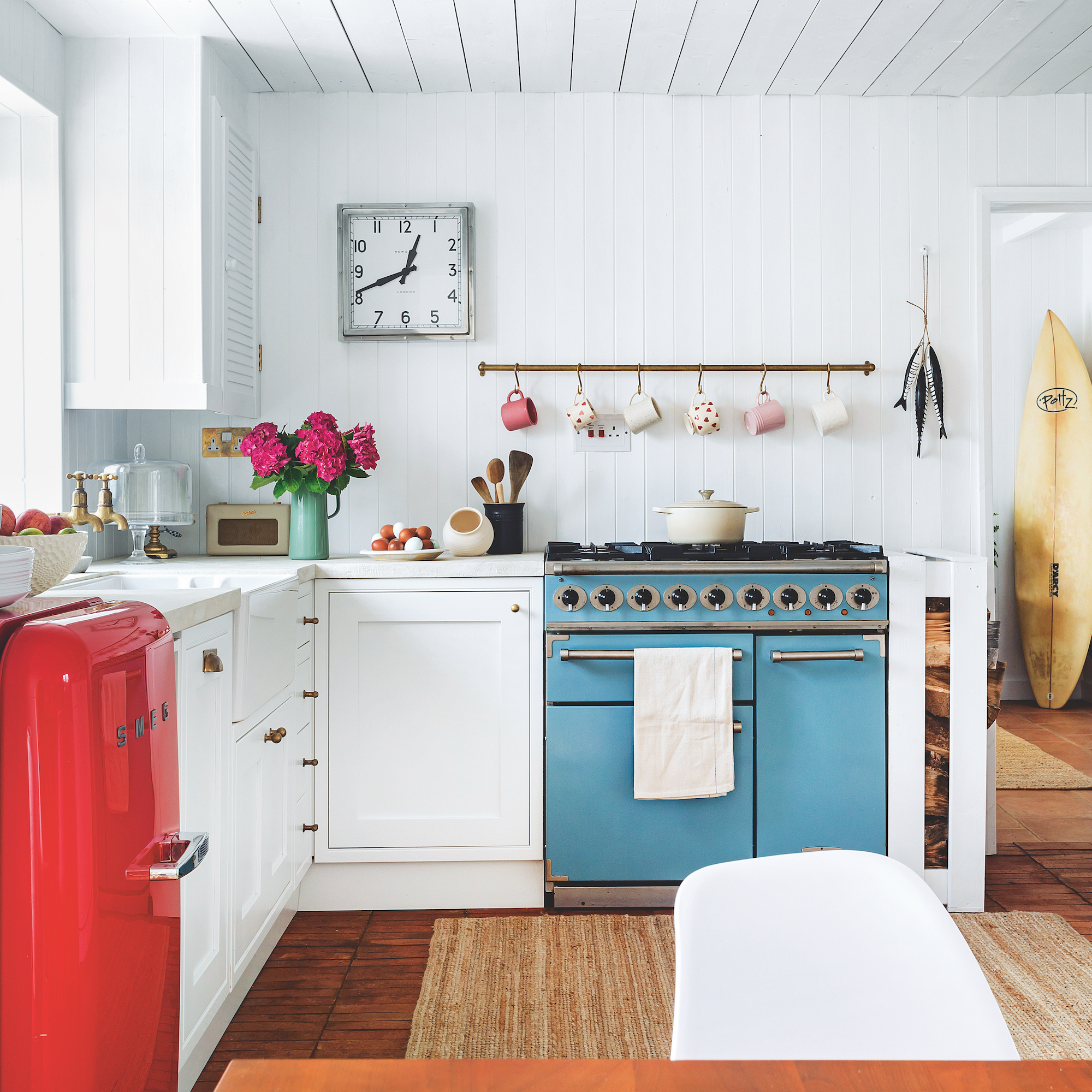 Coastal style kitchen with white walls and cabinets, blue stove and red american-style fridge