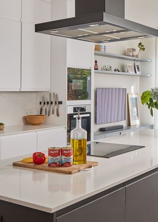 White, modern kitchen with ingredients for tomato sauce out on the counter