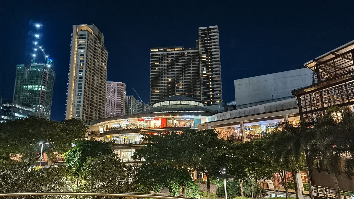 A vibrant cityscape at night, adorned with towering buildings and surrounded by lush trees