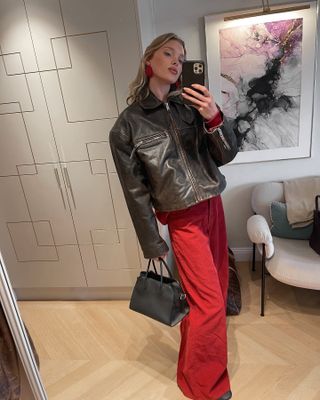 Elsa Hosk mengenakan jaket kulit, celana merah, dan tas Margaux The Row.