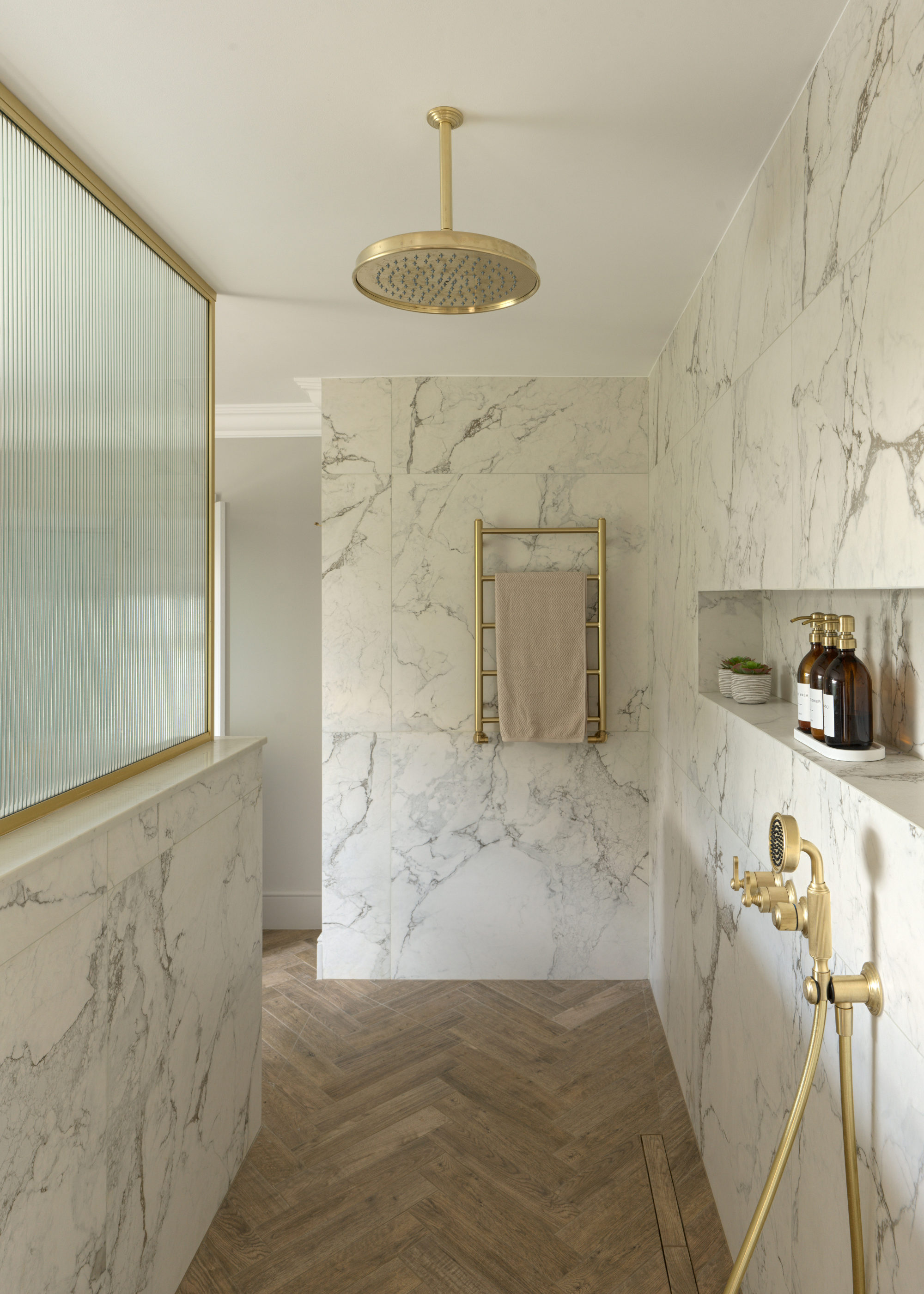 walk-in shower with herringbone wood floors and large format marble tiles