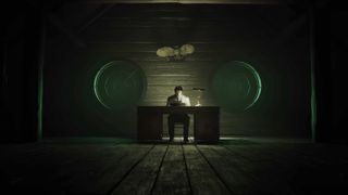 Alan Wake sitting at his desk in the Cauldron Lake cabin
