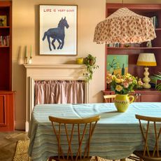 Dining room with oversized fabric lamp shade above table and horse print above fireplace
