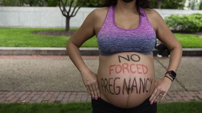 Pregnant woman with "no forced pregnancy" written on her belly
