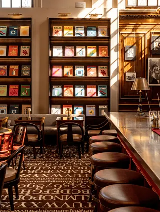 Maison Assouline's plush, sumptuous interiors feature literature-inspired, brown carpeted floors, leather furniture, and walls filled with books.