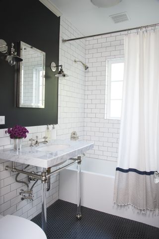 Bathroom with basin and tub with shower over and white subway tile